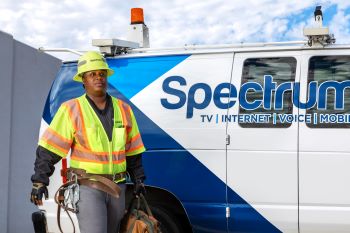 Technician wearing a work helmet holding a container labeled Spectrum. 